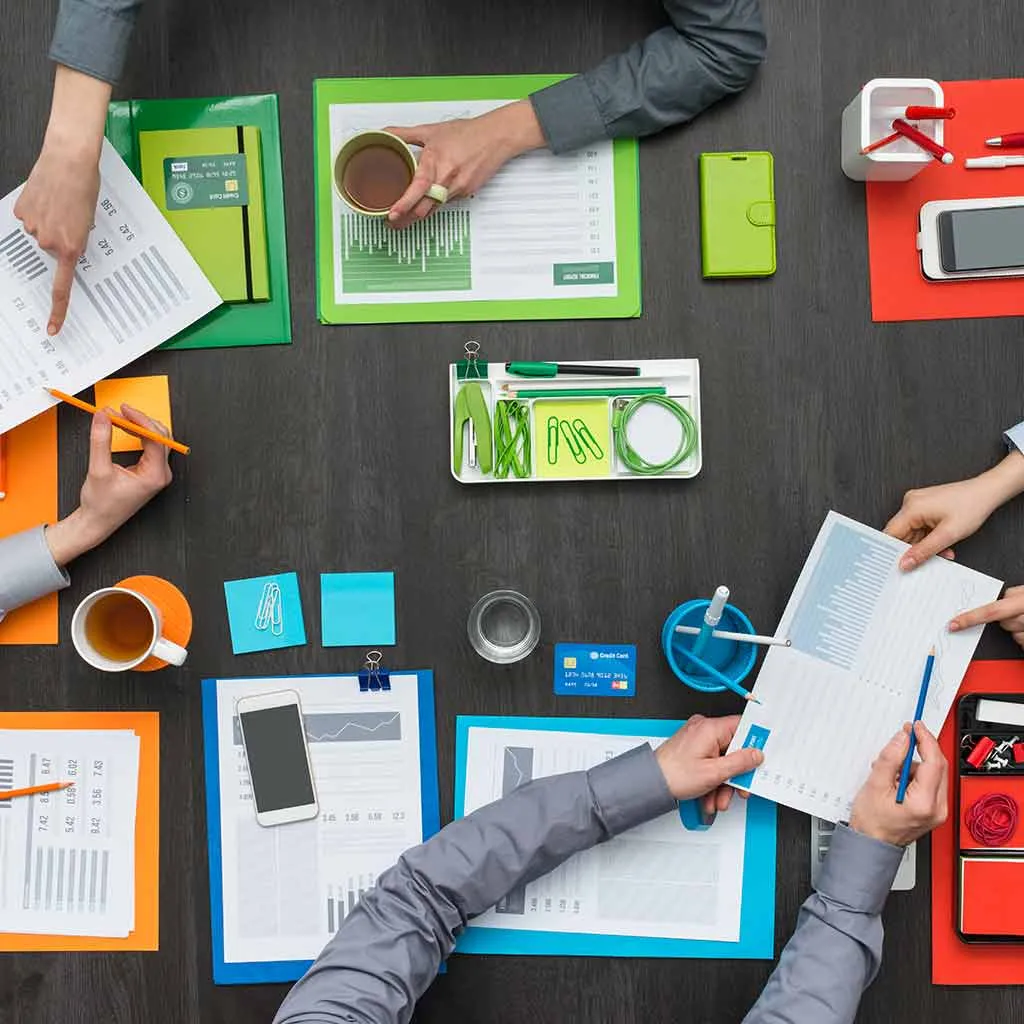 Colleghi seduti a un tavolo d'ufficio mentre progettano lavori di comunicazione digitale