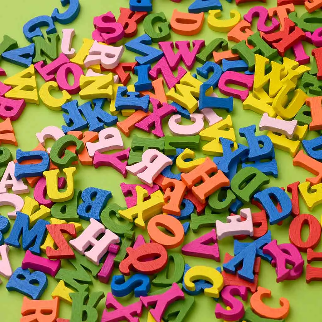 Lettere in legno colorate e sparpagliate su una base verde